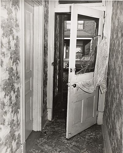 Hallway with broken door and lace curtain askew