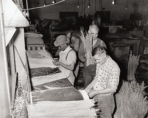 Men bundling straw for brooms