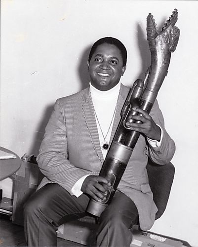 Musician Oliver Nelson holding an instrument, possibly saxophone, with an animal or monster shaped bell