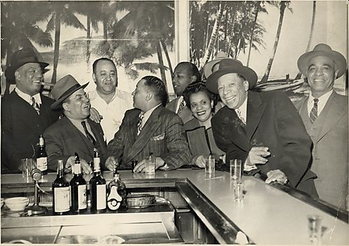 Eight men, including Gus Greenlee third from left, and a woman, at the bar of Crawford Grill no.1