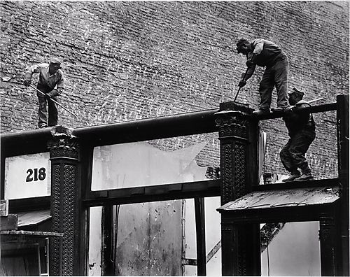 [workers demolishing building facade]