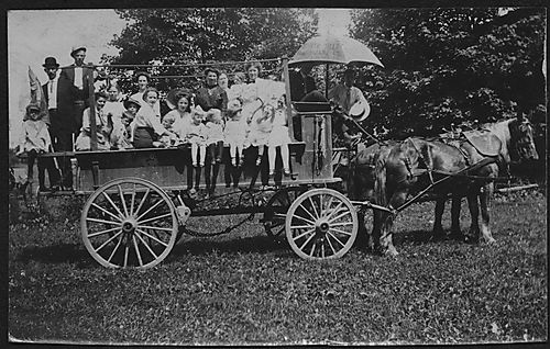 Group of people posing on a horse drawn wagon