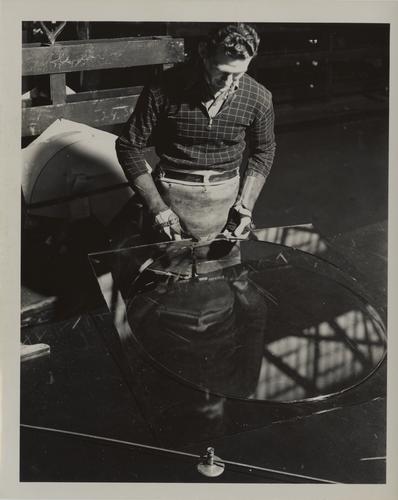 Employee hand-cutting glass in circular shape