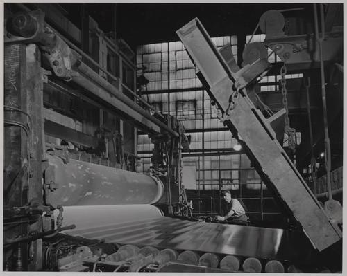 Employee examining glass ribbon as it emerges from tank