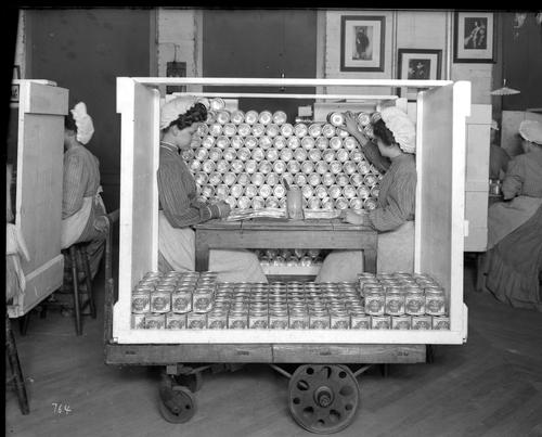 Two Heinz employees labeling cans of baked beans 
