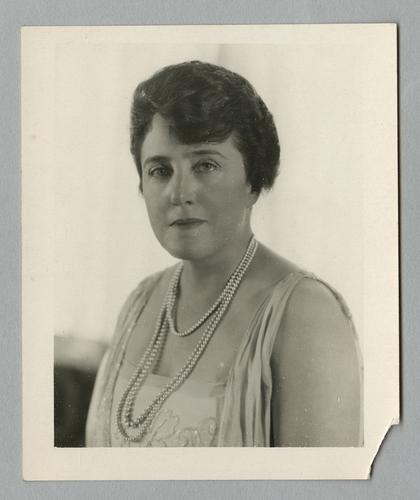 Mary Roberts Rinehart portraits in white flowered dress, standing by window
